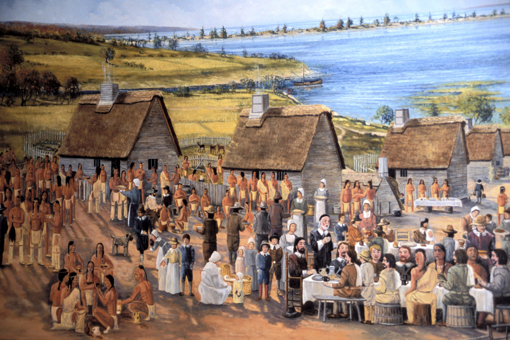 Artist's rendering of the first Thanksgiving, 1621. William Bradford, seated at the table, is presiding over the feast in his role as governor.